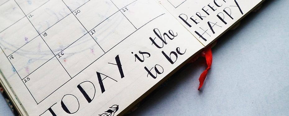 Close-up of a planner page with handwritten text "Today is the perfect day to be" alongside decorative elements, emphasizing organization and motivation.