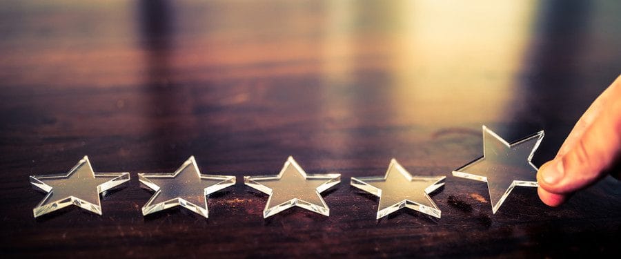 Three silver star-shaped decorations arranged on a wooden surface, representing ratings or reviews.