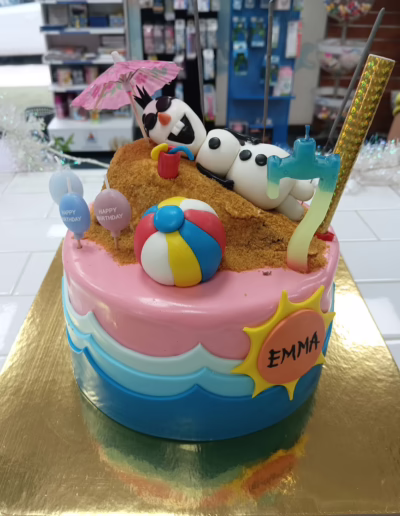 Birthday cake decorated with a sandy beach theme featuring a fondant Olaf character, colorful beach balls, and festive birthday decorations, ideal for a children's birthday celebration.
