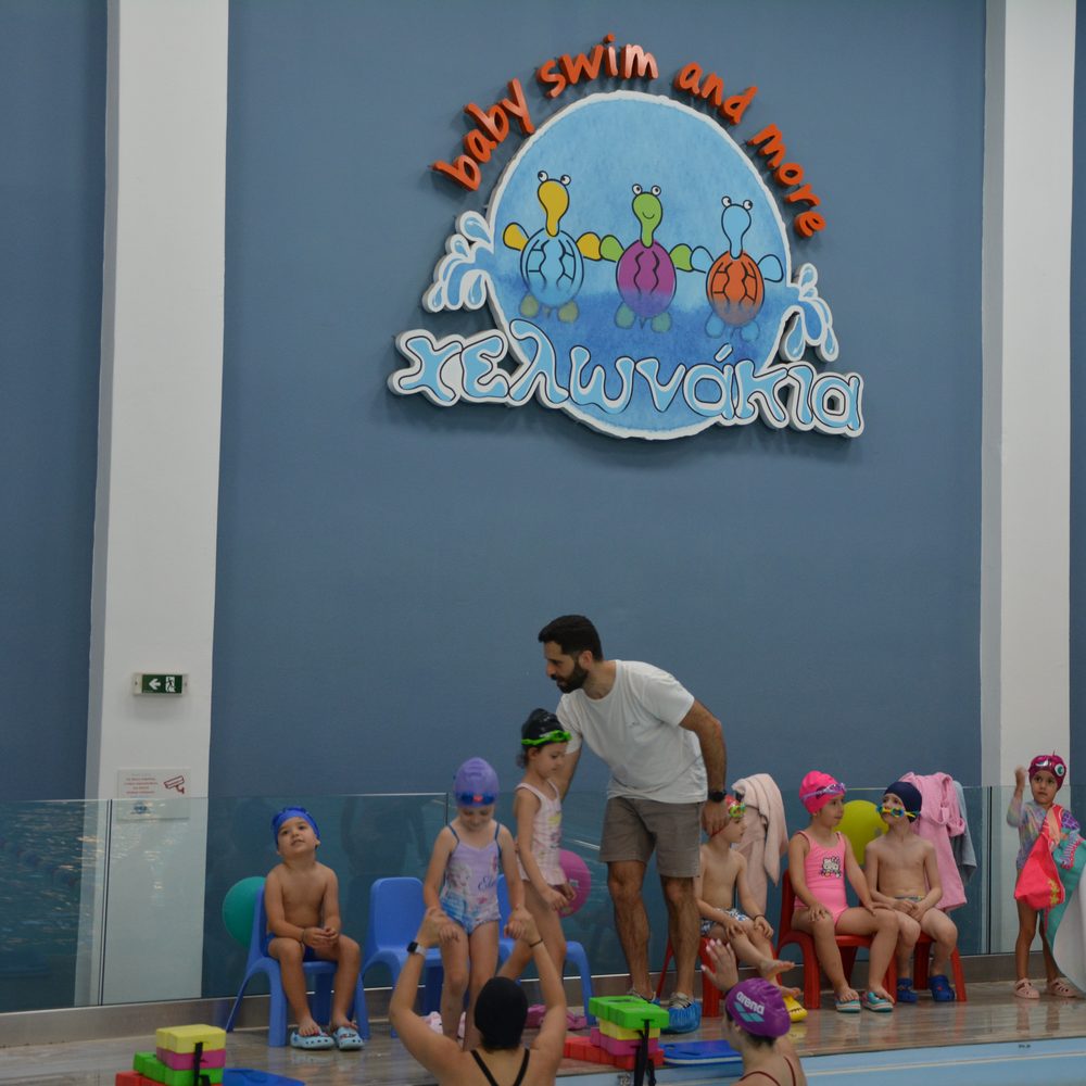 Παιδιά με σκουφάκια και παντόφλες περιμένουν στο deck της πισίνας στα Χελωνάκια